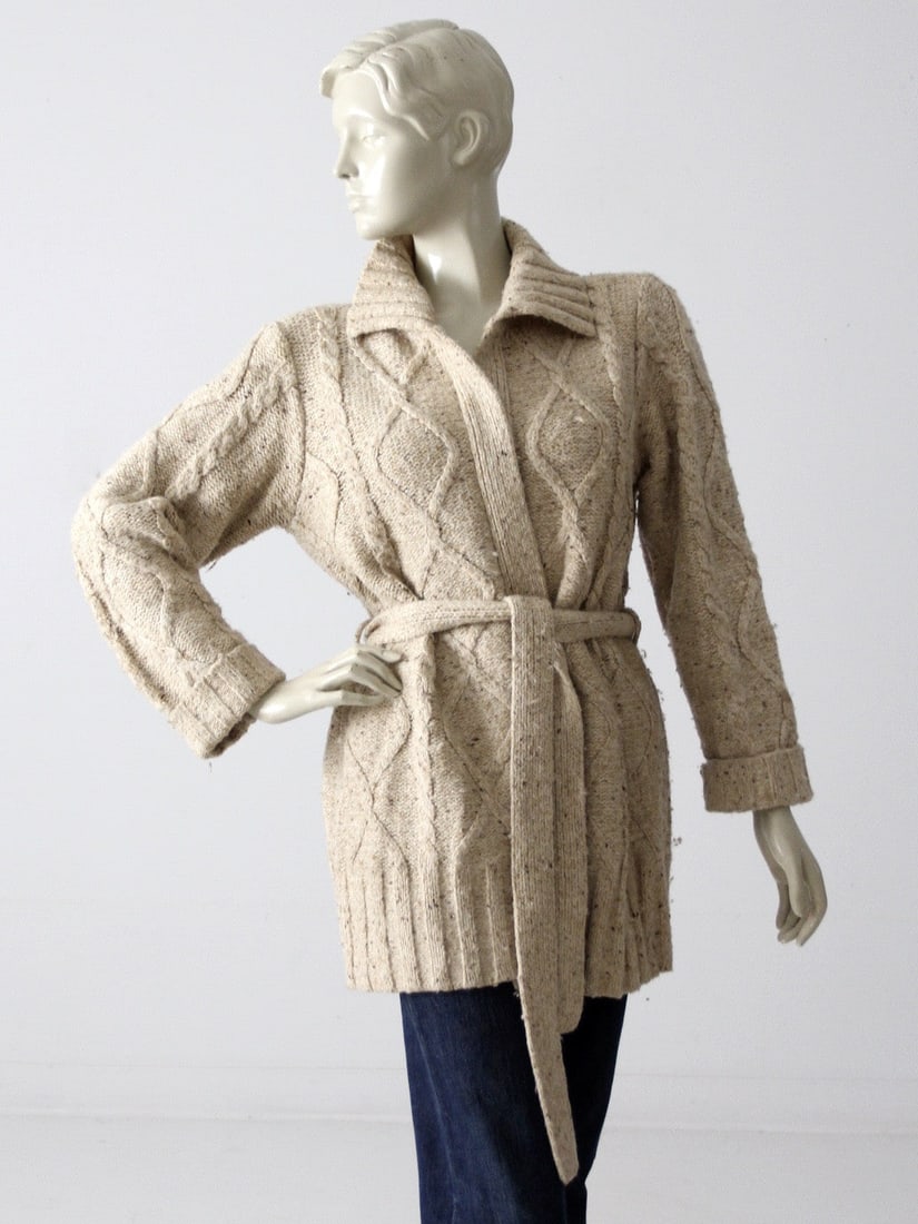 1970s Vintage Oatmeal Cable Knit Wrap Cardigan with Belt: 1970s Vintage Oatmeal Cable Knit Wrap Cardigan with Belt Step back into the 1970s with this charming vintage cable knit cardigan. Crafted from a soft oatmeal knit, this wrap-style sweater features a c