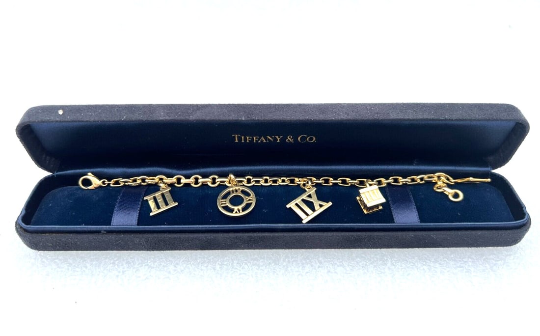 Tiffany & Co 18K Yellow Gold Atlas Charm Bracelet with 5 Charms and Box: Tiffany & Co 18K Yellow Gold Atlas Charm Bracelet with 5 Charms and Box Discover the elegance of this Tiffany & Co. Atlas bracelet, crafted from luxurious 18K yellow gold. This exquisite charm bracele
