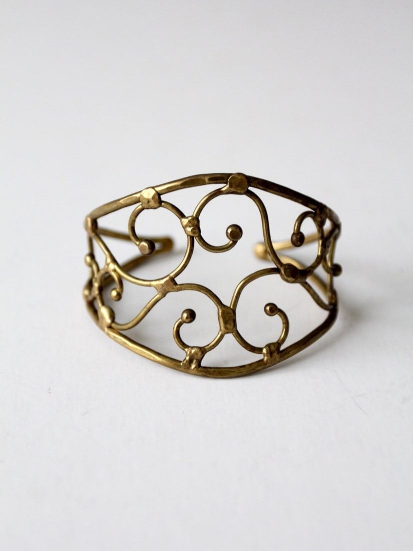 Vintage Brutalist Brass Cuff with Wide Scroll Design: Vintage Brutalist Brass Cuff with Wide Scroll Design Discover a unique piece from our Stylist's Collection: a vintage brutalist style brass cuff. This hand-crafted bracelet showcases a striking wide s