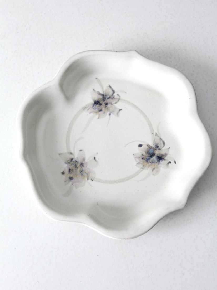 Handmade Vintage Studio Pottery Plate with Floral Design 12 In: Handmade Vintage Studio Pottery Plate with Floral Design 12 In This vintage studio pottery plate is a charming piece, showcasing a unique handmade design. The white ceramic platter features a scallope