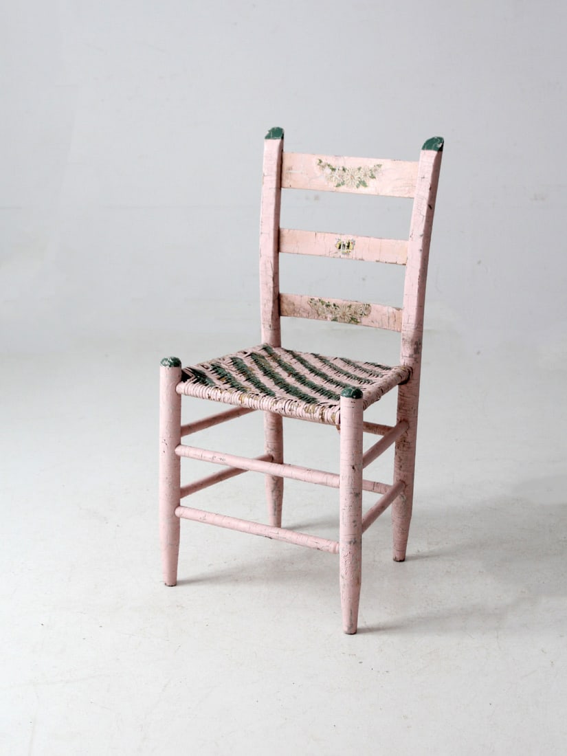 Antique Pastel Pink Ladder Back Chair with Cane Seat: Antique Pastel Pink Ladder Back Chair with Cane Seat This delightful antique chair showcases a soft pastel pink painted finish complemented by woven cane seating and charming green accents. The ladder