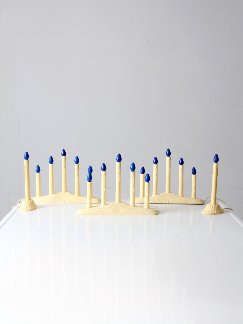 Vintage Mid-Century Electric Candoliers Set with Blue Bulbs: Vintage Mid-Century Electric Candoliers Set with Blue Bulbs This vintage set of electric candoliers features elegant ivory bases complemented by deep blue bulbs that emit a warm, seasonal glow. Design