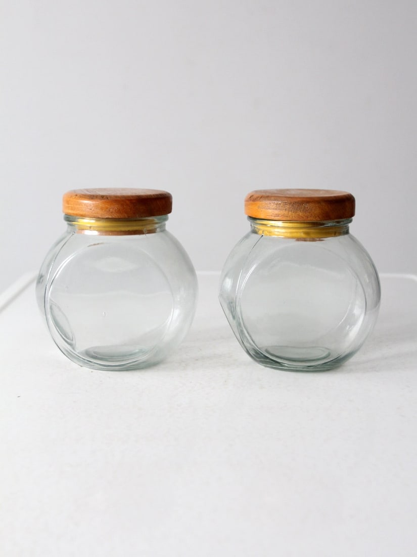 Timeless Vintage Glass Candy Jar Set with Wooden Lids: Timeless Vintage Glass Candy Jar Set with Wooden Lids This charming pair of vintage glass candy jars combines functionality with a timeless design. Their rounded shape with flat sides allows them to r