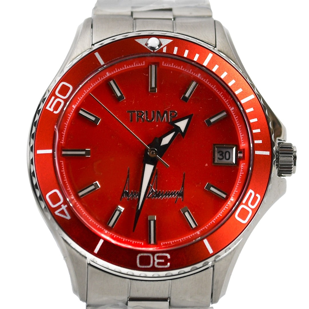 Red Dial Stainless Steel Automatic Trump Wristwatch with Box and Booklet: Red Dial Stainless Steel Automatic Trump Wristwatch with Box and Booklet This pre-owned wristwatch features a striking red analog dial and a stainless steel case and bracelet. It operates with automat