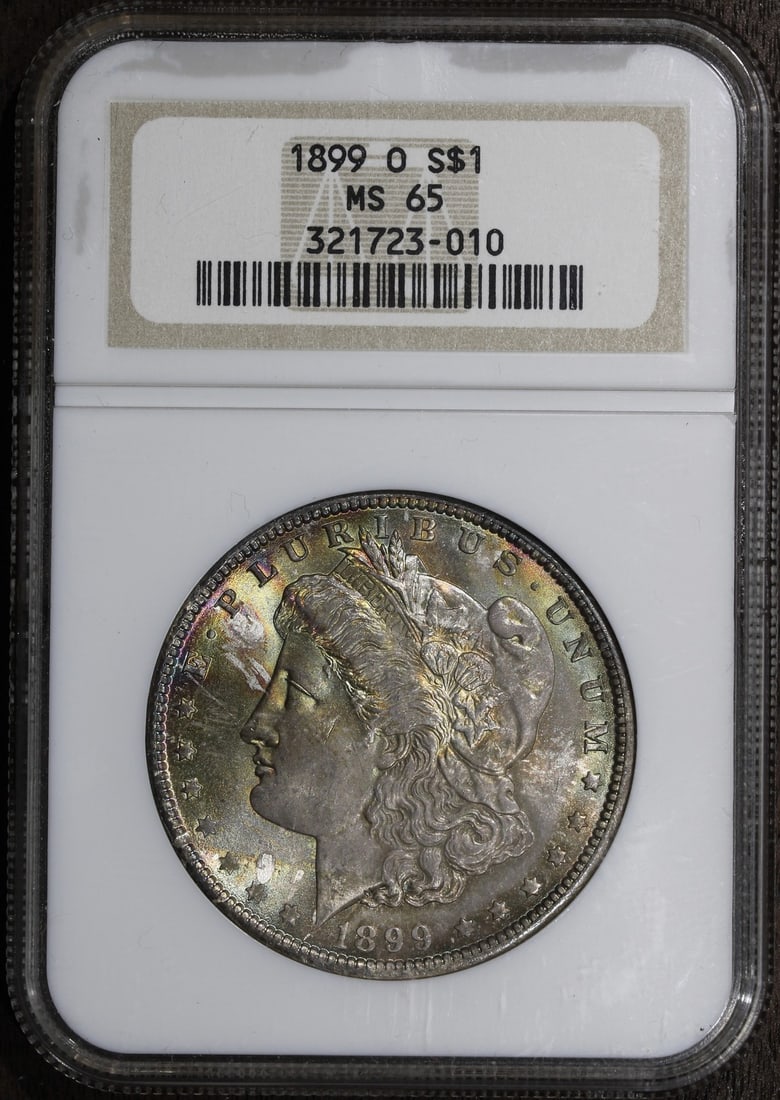 1899-O Morgan Silver Dollar MS65 NGC with Colorful Tone: 1899-O Morgan Silver Dollar MS65 NGC with Colorful Tone This stunning 1899-O Morgan Silver Dollar showcases a lovely colorful tone, making it a remarkable addition to any collection. With a denominati