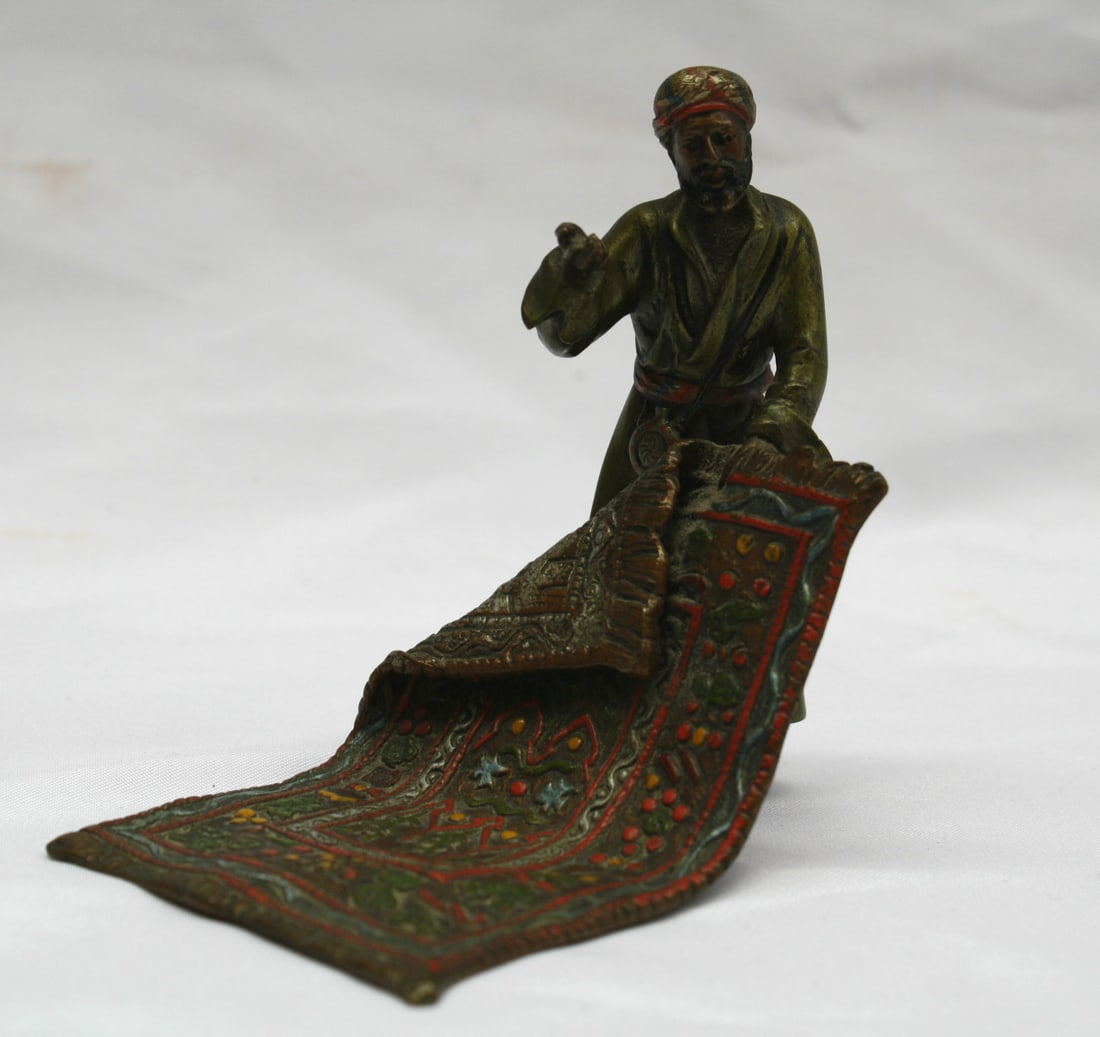19th Century Austrian Hand Painted Bronze Rug Seller Sculpture: 19th Century Austrian Hand Painted Bronze Rug Seller Sculpture This exquisite late 19th-century Austrian bronze sculpture features a hand-painted depiction of an Arab man selling a rug. Crafted betwee