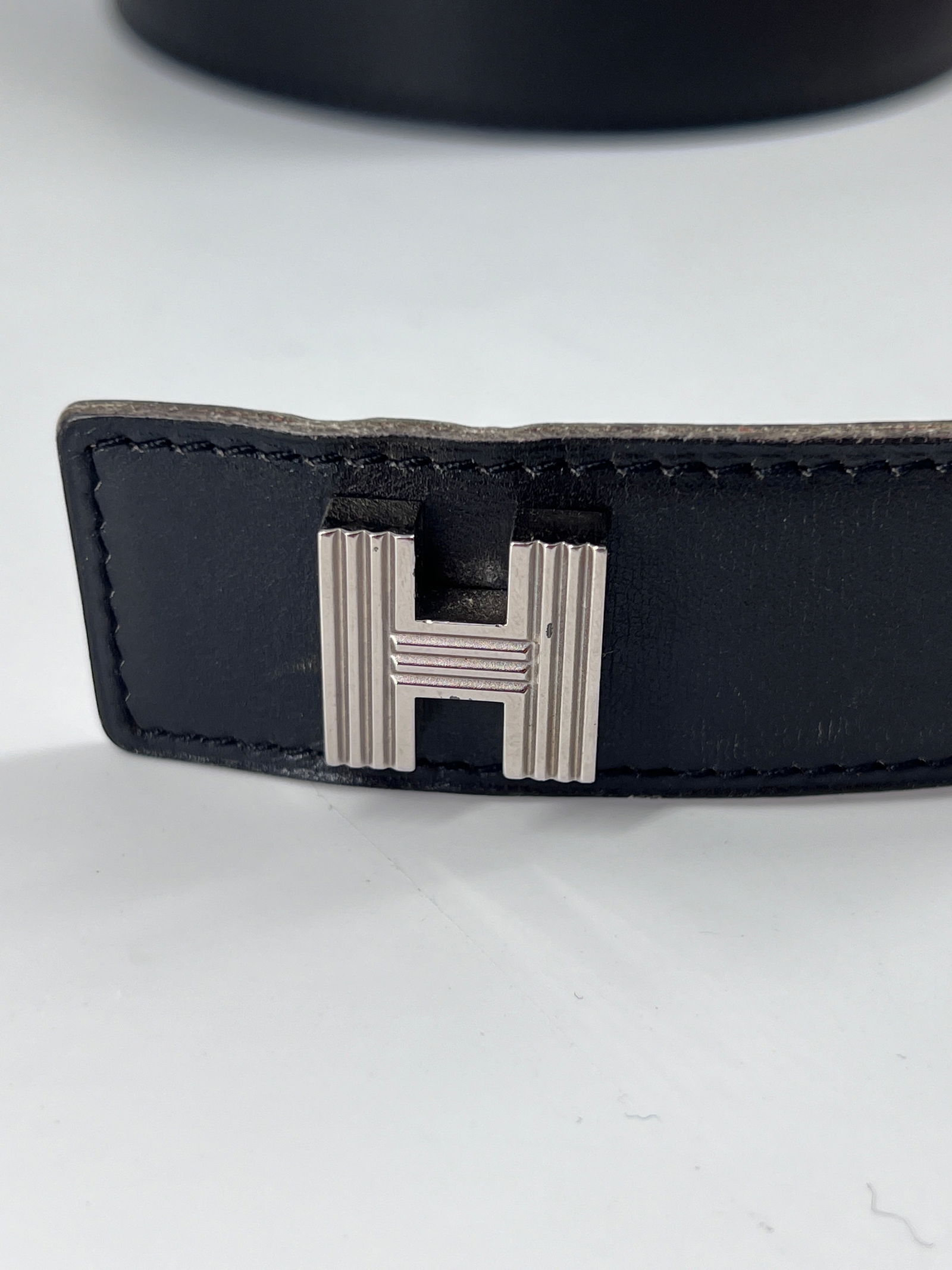 Black Hermes Lucky H Women's Belt with Adjustable Holes: Black Hermes Lucky H Women's Belt with Adjustable Holes This pre-owned Hermes Lucky H belt in black is designed for women. It shows signs of wear, including slightly damaged adjustment holes along its