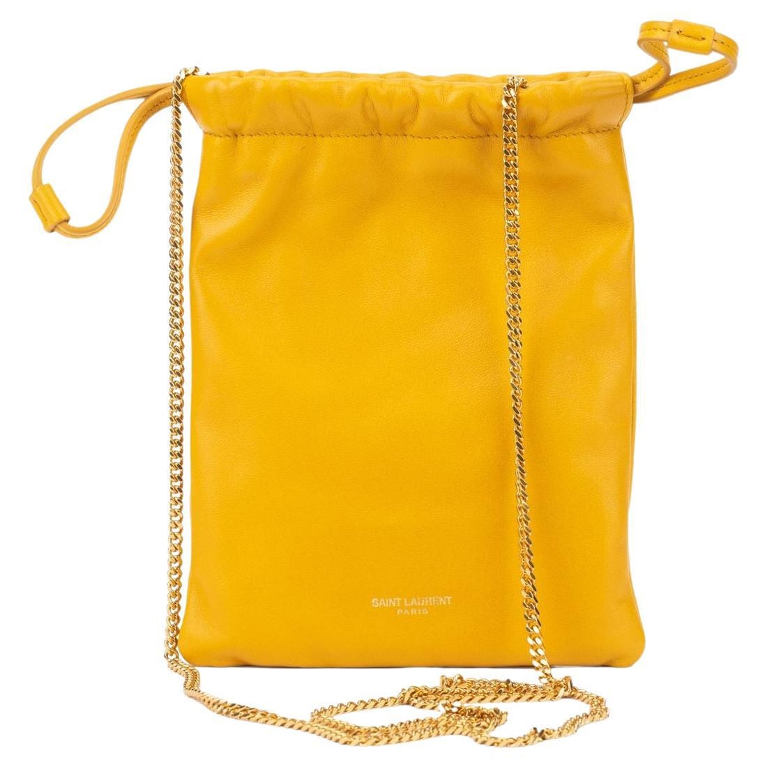Yves Saint Laurent Saffron Drawstring Bag with Gold Tone Chain: Yves Saint Laurent Saffron Drawstring Bag with Gold Tone Chain This exquisite Yves Saint Laurent drawstring bag is crafted from luxurious lambskin in a vibrant saffron shade, complemented by elegant g