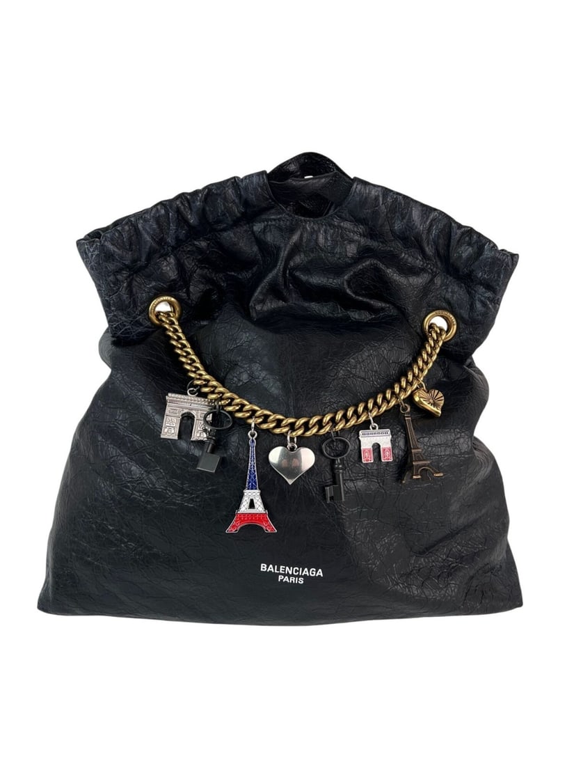Balenciaga Crush Medium Black Leather Tote Bag with Charms: Balenciaga Crush Medium Black Leather Tote Bag with Charms Introducing the Balenciaga Leather Crush Medium Tote Bag, a stylish accessory that embodies designer elegance. Crafted from premium black lea