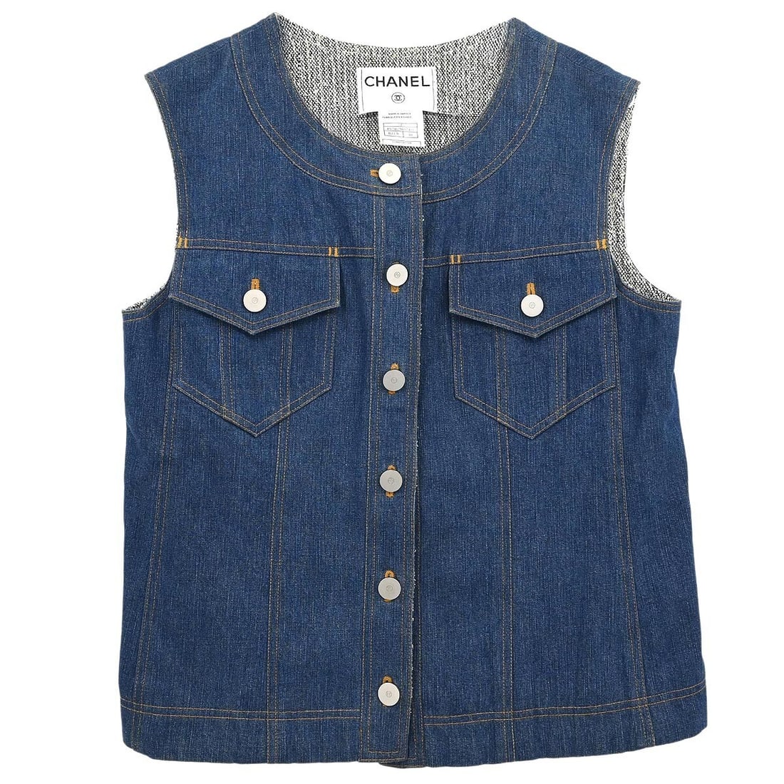 Chanel Vintage Blue Denim Sleeveless Vest Jacket #40: Chanel Vintage Blue Denim Sleeveless Vest Jacket #40 This vintage Chanel sleeveless vest denim jacket in blue is crafted from 100% cotton, ensuring comfort and durability. The mid-length design featur