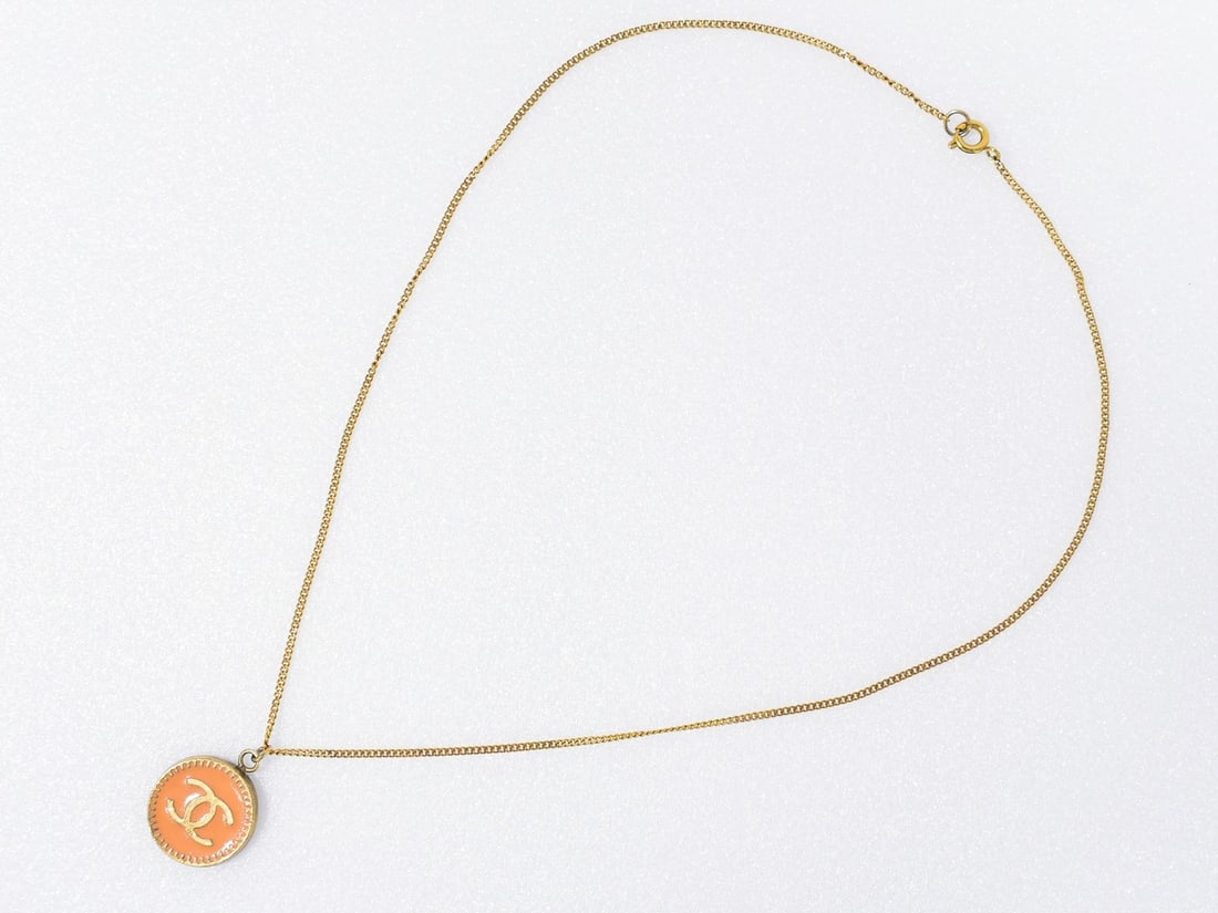 Vintage Chanel Necklace with CC Logo Circular Gold Pendant: Vintage Chanel Necklace with CC Logo Circular Gold Pendant This pre-owned Chanel vintage CC round pendant necklace features gold plating. The necklace is in good condition with visible peeling of the