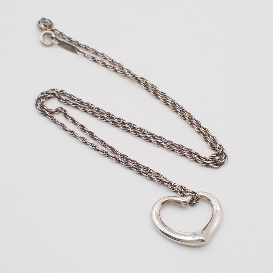 Elsa Peretti Open Heart Silver Necklace by Tiffany & Co.: Elsa Peretti Open Heart Silver Necklace by Tiffany & Co. This pre-owned Tiffany & Co. Elsa Peretti Open Heart pendant necklace is crafted in silver and is designed for women. It is in very good condit