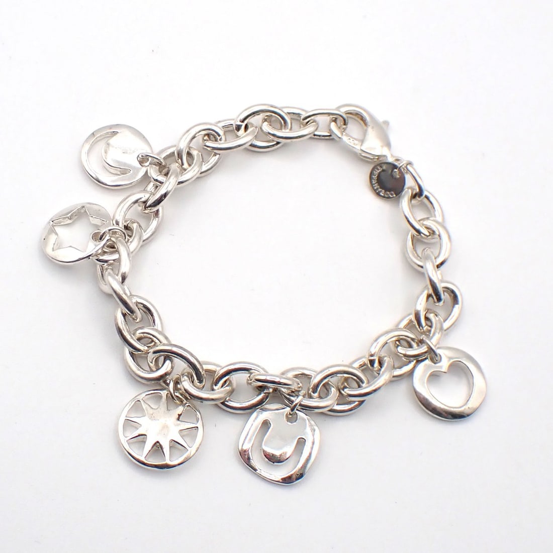 Stencil Charms Silver Bracelet by Tiffany & Co.: Stencil Charms Silver Bracelet by Tiffany & Co. This pre-owned Tiffany & Co. Stencil Charms bracelet is crafted from silver and designed for women. It is in very good condition, exhibiting minor scuff