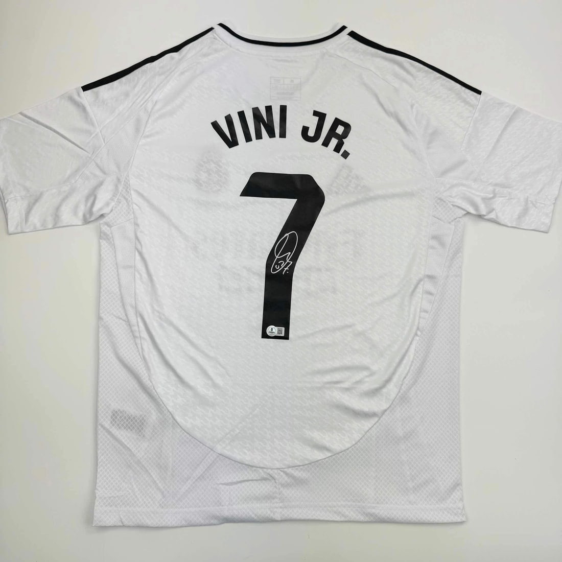 Vinicius Jr. Autographed Real Madrid #7 Soccer Jersey BAS COA: Vinicius Jr. Autographed Real Madrid #7 Soccer Jersey BAS COA Celebrate your love for soccer with this authentic autographed Vini Vinicius Jr. #7 Real Madrid white soccer jersey. This custom jersey, d