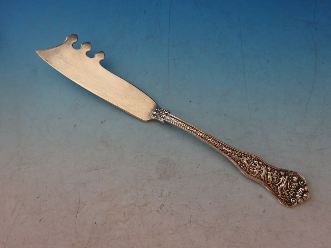 Tiffany & Co Olympian Sterling Silver Cheese Knife with Pick 7 1/4": Tiffany & Co Olympian Sterling Silver Cheese Knife with Pick 7 1/4" This exquisite cheese knife, crafted by Tiffany & Co., showcases the renowned Olympian pattern. Made from high-quality sterling silv
