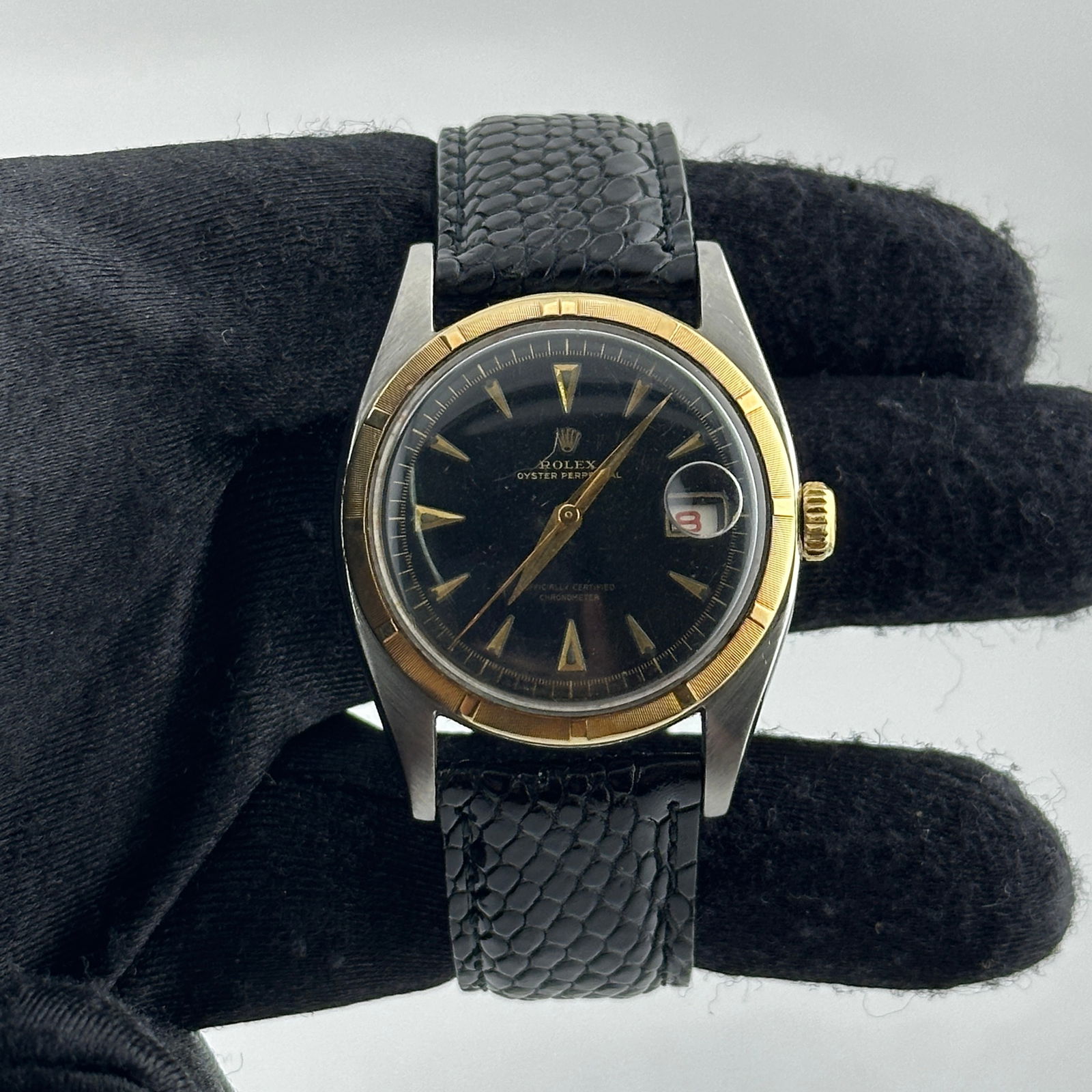 Oyster Perpetual Ref 6105 Black Dial Watch with Aftermarket Leather Strap: Oyster Perpetual Ref 6105 Black Dial Watch with Aftermarket Leather Strap This Rolex Oyster Perpetual features a black dial with gold stick markers and an engine-turned bezel. It is fitted with an aft