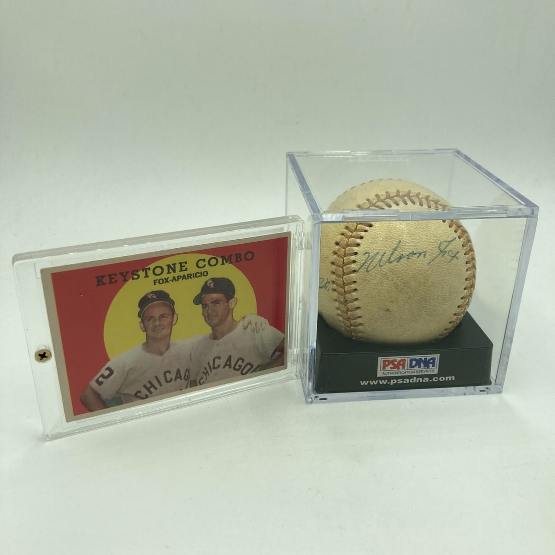 Nellie Fox Luis Aparicio Signed Baseball with 1959 Topps Card PSA DNA COA: Nellie Fox Luis Aparicio Signed Baseball with 1959 Topps Card PSA DNA COA This unique collectible features a vintage 1950s baseball signed by two MLB Hall of Famers, Nellie Fox and Luis Aparicio, both
