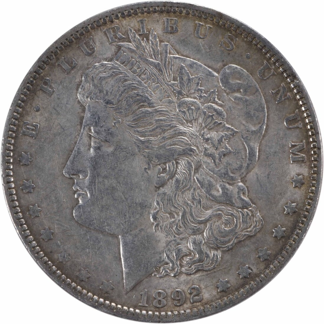 1892 Morgan Silver Dollar AU Uncertified 90% Silver Coin: 1892 Morgan Silver Dollar AU Uncertified 90% Silver Coin This 1892 Morgan Silver Dollar showcases the artistry of designer George T. Morgan. It is composed of 90% silver and 10% copper, making it a va