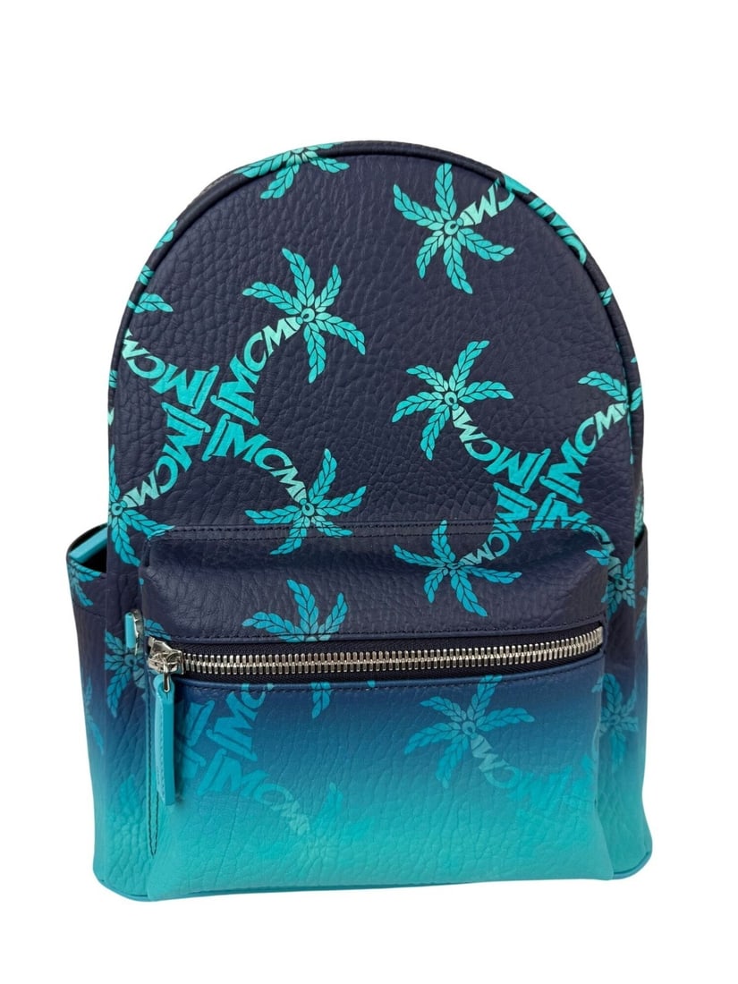 MCM Stark Ceramic Blue Gradation Palm Canvas Backpack with Silver Hardware: MCM Stark Ceramic Blue Gradation Palm Canvas Backpack with Silver Hardware The MCM Stark Ceramic Blue Gradation Palm Backpack features a crescent shape and a striking blue palm tree pattern on coated
