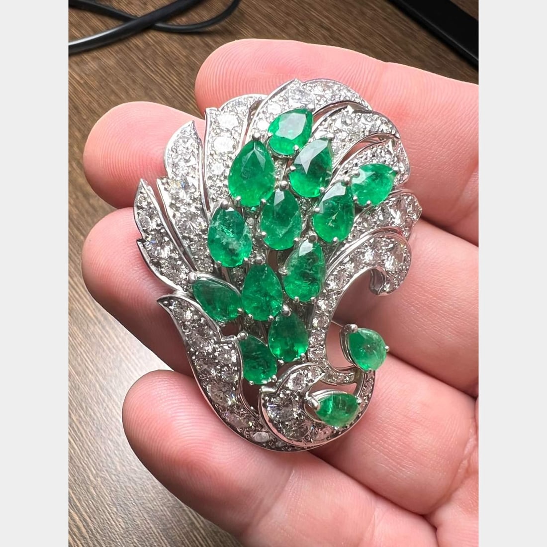 Platinum Brooch with 14 Emeralds and 94 Diamonds 2 Inch: Platinum Brooch with 14 Emeralds and 94 Diamonds 2 Inch This exquisite Platinum Emerald & Diamond Brooch features a stunning combination of vibrant emeralds and sparkling diamonds. Weighing 26.8 grams