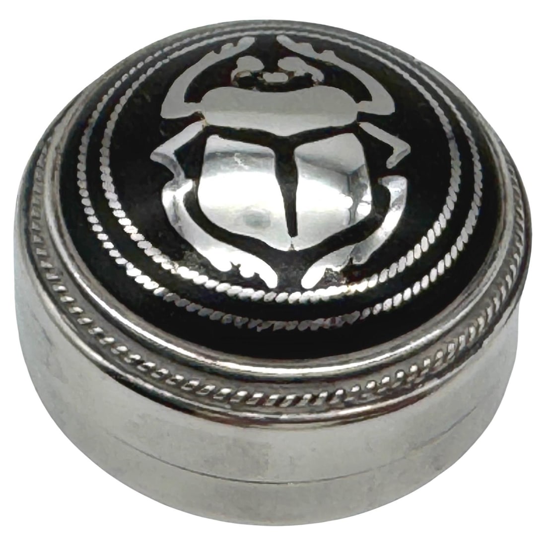 Mid-20th Century Egyptian Niello Enamel Silver Pill Box with Scarab Decoration: Mid-20th Century Egyptian Niello Enamel Silver Pill Box with Scarab Decoration This Egyptian pill box from the mid-20th century features a circular sterling silver form with intricate niello enamel de