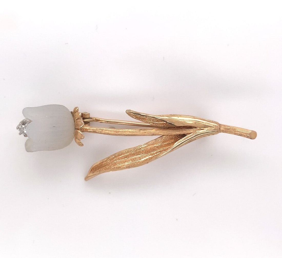 18k Gold Tulip Flower Pin with Chalcedony and Diamond Accent: 18k Gold Tulip Flower Pin with Chalcedony and Diamond Accent This exquisite 18k gold pin features a beautifully carved natural chalcedony tulip flower adorned with a diamond accent. The intricate deta