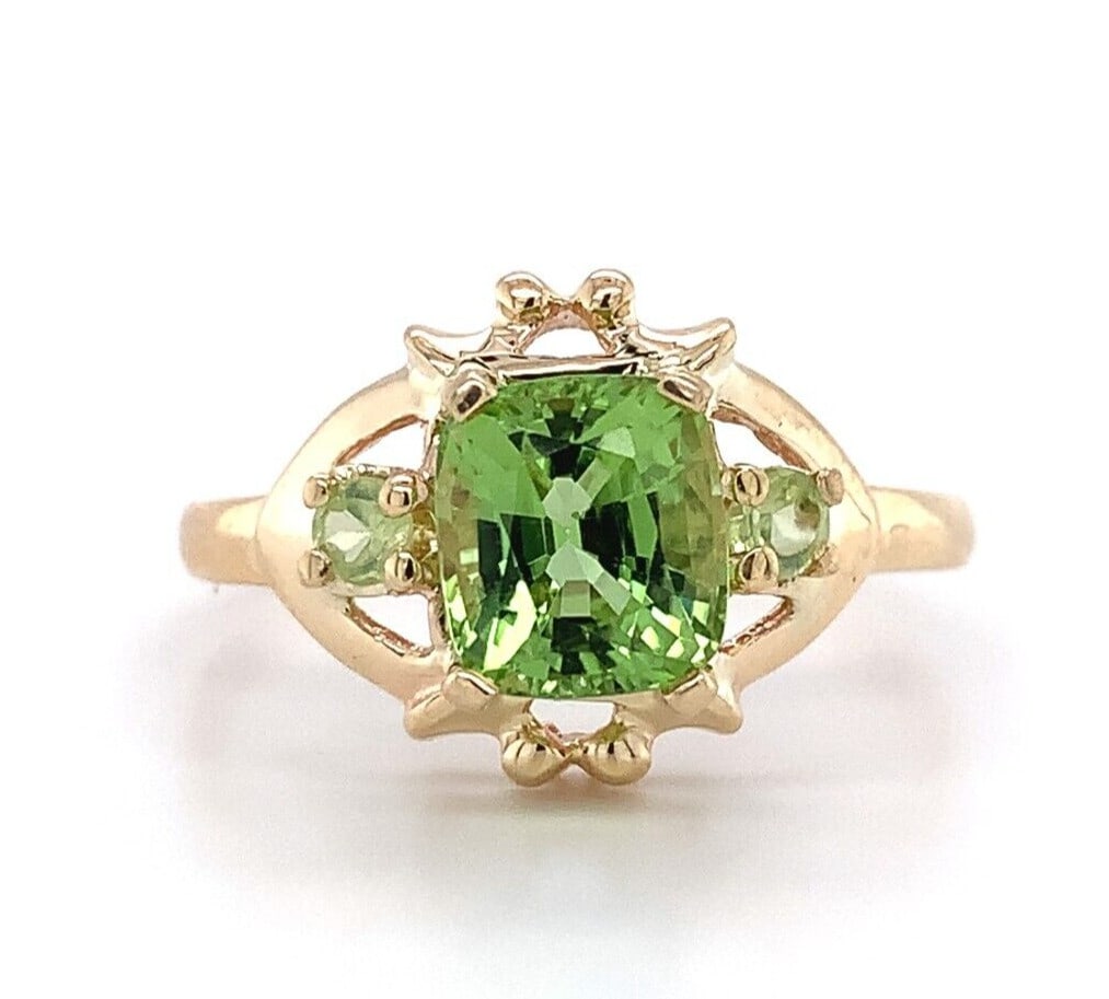 Vintage 10k Yellow Gold Three-Stone Peridot Ring with Cushion Cut Center: Vintage 10k Yellow Gold Three-Stone Peridot Ring with Cushion Cut Center This vintage ring showcases a genuine natural peridot as its centerpiece, featuring a cushion cut peridot weighing