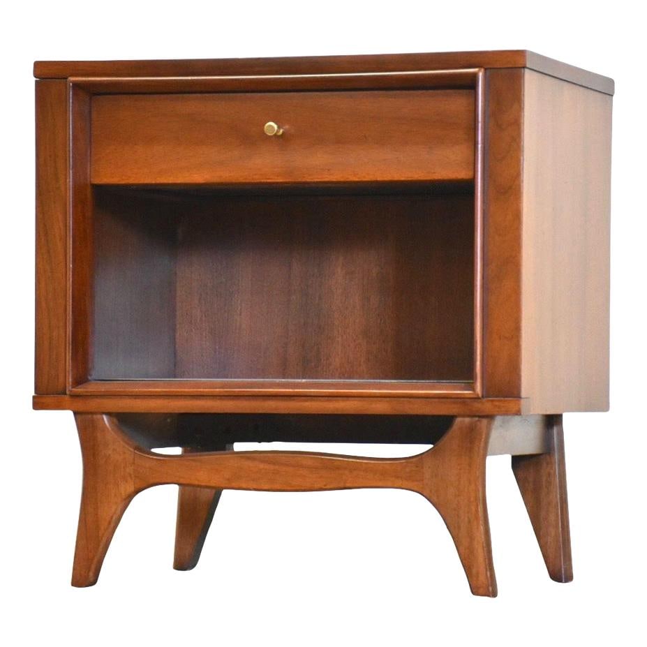 Mid Century Modern Walnut Nightstand with Brass Knob: Mid Century Modern Walnut Nightstand with Brass Knob This mid-century modern walnut nightstand features a sleek design with a single drawer and a lower shelf for additional storage. The elegant brass