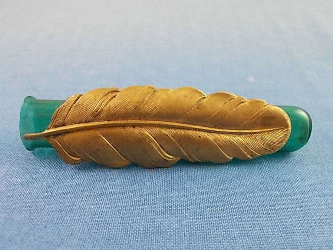 Victorian Teal Glass Posey Pin with Gilt Brass Feather 1900s: Victorian Teal Glass Posey Pin with Gilt Brass Feather 1900s This exquisite teal glass posey pin features a stunning large gilt brass feather, dating back to the early 1900s to the 1920s. The pin, mea