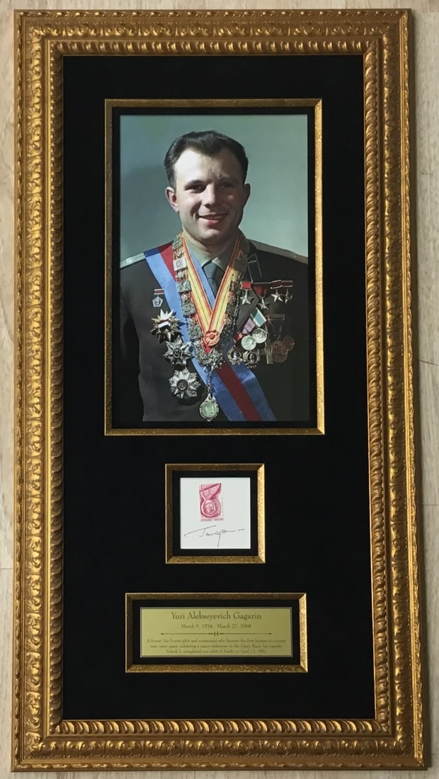 Yuri Gagarin Signed Card with LOA Museum Framed 1961 Space Theme: Yuri Gagarin Signed Card with LOA Museum Framed 1961 Space Theme This signed card celebrates Yuri Alekseyevich Gagarin, the first man in space, featuring his autograph alongside a commemorative stamp.