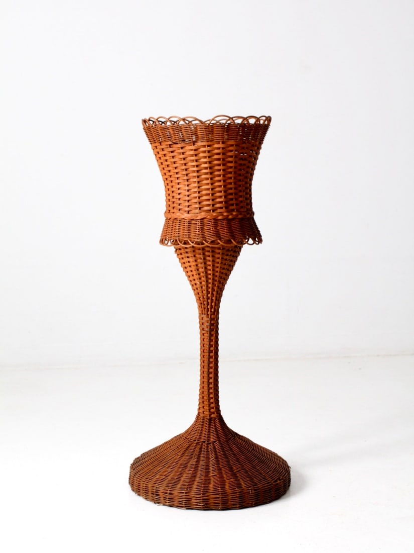 Vintage Wicker Pedestal Planter with Removable Basket: Vintage Wicker Pedestal Planter with Removable Basket This vintage wicker pedestal planter stand features an elegant sculptural silhouette with a warm honeyed tone. The flared basket top is supported