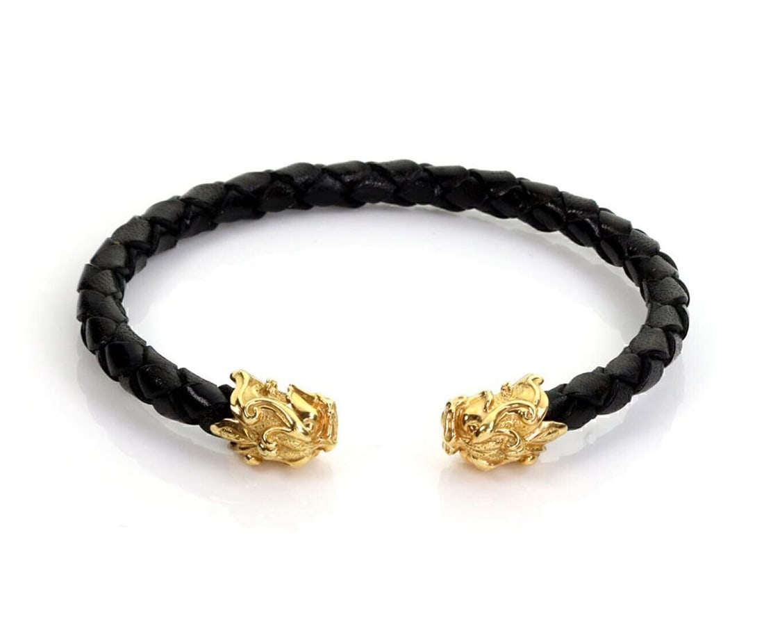 18k Yellow Gold Cuff Bracelet with Woven Leather and Dragon Heads by Carrera y Carrera: 18k Yellow Gold Cuff Bracelet with Woven Leather and Dragon Heads by Carrera y Carrera This cuff bracelet by Carrera y Carrera is crafted from 18k yellow gold and features a woven leather cord. The de