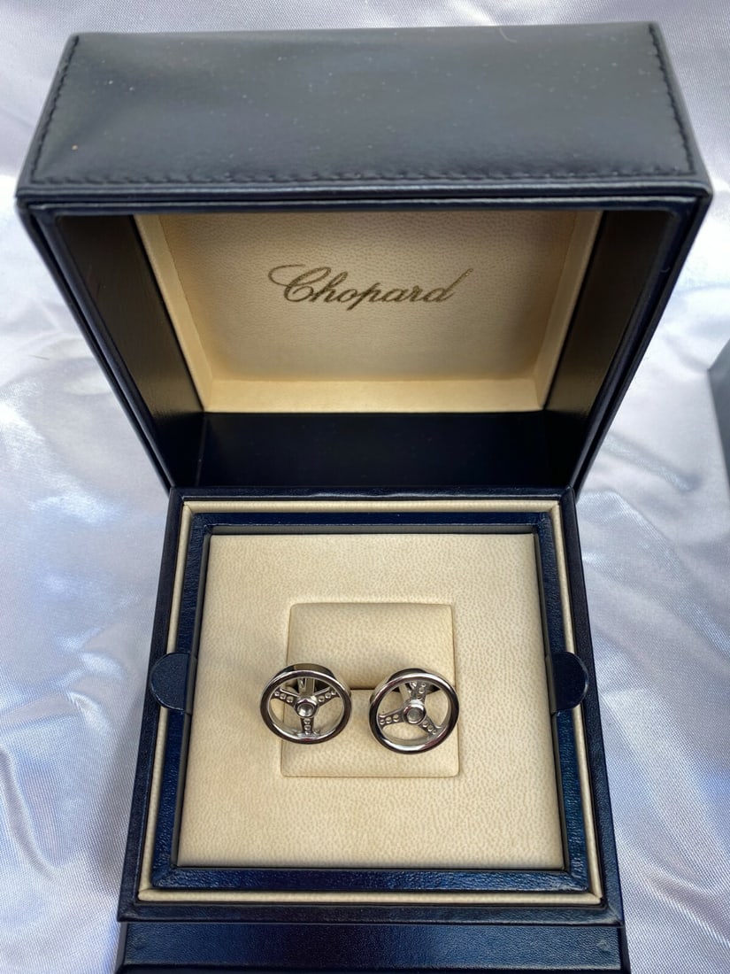 Chopard 18K White Gold Steering Wheel Cufflinks with 3 Leather Boxes: Chopard 18K White Gold Steering Wheel Cufflinks with 3 Leather Boxes Elevate your formal attire with these exquisite Chopard Steering Wheel Cufflinks, crafted from luxurious 18K white gold. These cuff