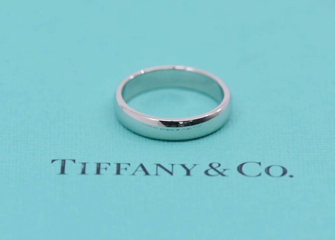 Platinum 950 Band by Tiffany Size 7 with Pouch: Platinum 950 Band by Tiffany Size 7 with Pouch This Tiffany & Co. ring is crafted from platinum with a metal purity of 950, featuring a classic design without a main stone. It is a pre-owned item and