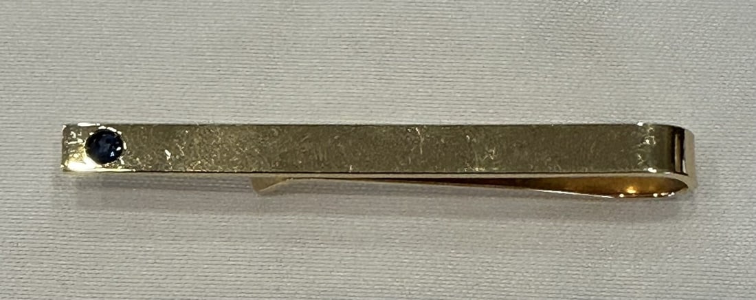 14K Gold Sapphire Tie Bar by KL with Hallmark: 14K Gold Sapphire Tie Bar by KL with Hallmark This exquisite 14K yellow gold tie bar features a stunning sapphire centerpiece, marked with the initials KL. Weighing approximately 5.60g, this tie bar m