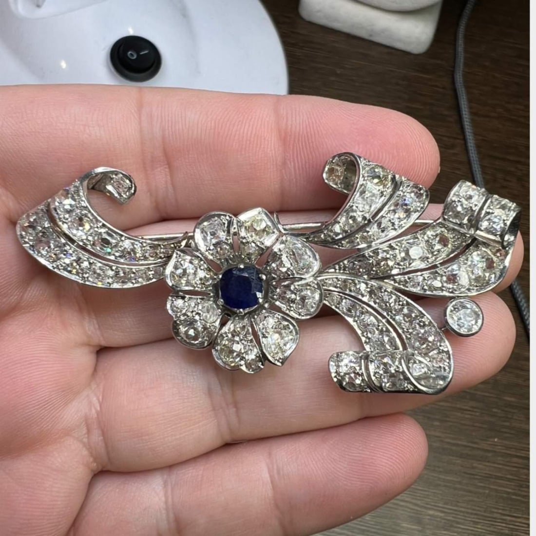 Art Deco Platinum Brooch with 1.00 Ct Sapphire and 72 Diamonds: Art Deco Platinum Brooch with 1.00 Ct Sapphire and 72 Diamonds This exquisite Art Deco brooch is crafted in platinum and features a stunning central sapphire weighing approximately 1.00 Ct. The brooch