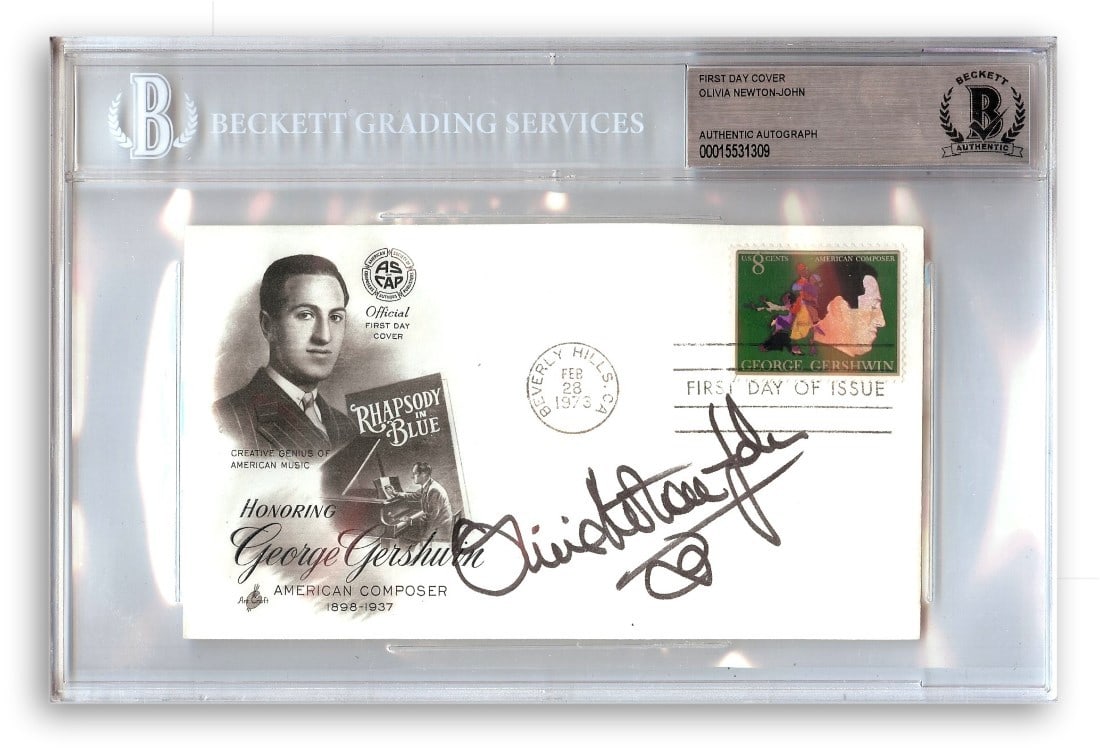 First Day Cover Signed by Olivia Newton John Beckett Authenticated: First Day Cover Signed by Olivia Newton John Beckett Authenticated This First Day Cover card has been autographed by Olivia Newton John, renowned actress and singer. The collectible comes encased in a