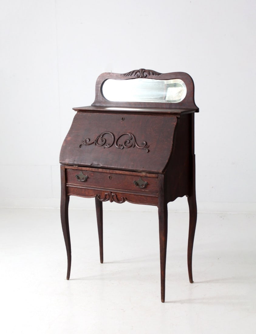 Early 1900s Larkin Style Antique Secretary Desk with Mirror: Early 1900s Larkin Style Antique Secretary Desk with Mirror This exquisite early 1900s antique secretary desk, crafted in the Larkin Style, showcases intricate carvings and a gracefully curved front t