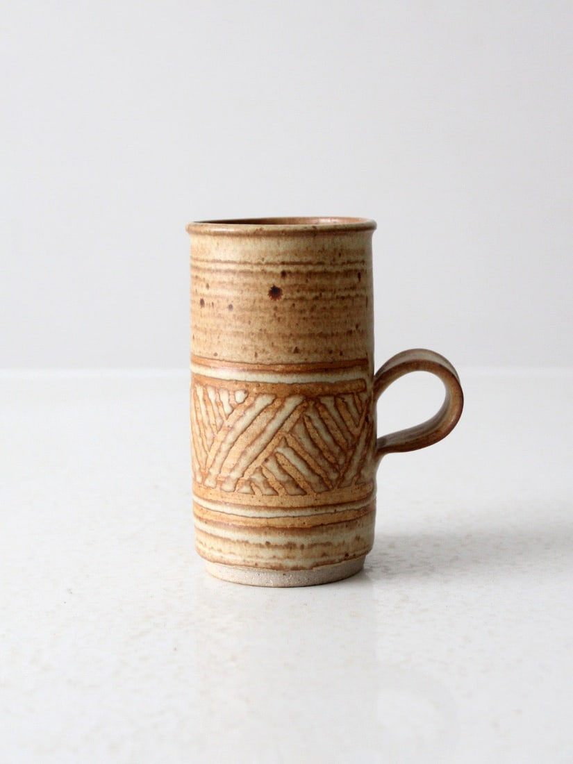 Signed Vintage Studio Pottery Mug with Geometric Band: Signed Vintage Studio Pottery Mug with Geometric Band This vintage studio pottery mug showcases a warm, earthy glaze adorned with subtle speckling, creating a unique and inviting aesthetic. A hand-etc