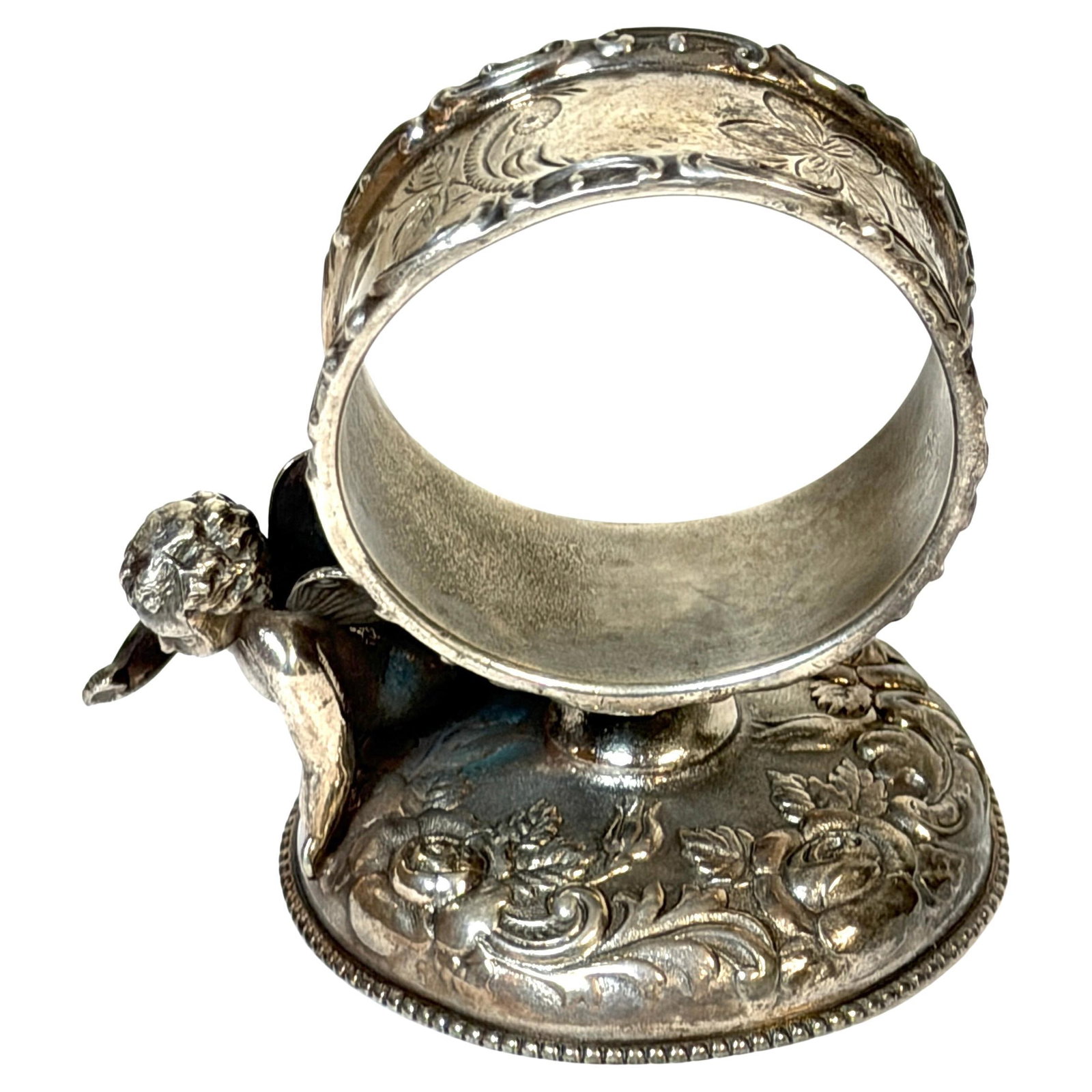 Wilcox Silverplate Napkin Ring with Victorian Cherub and Floral Motifs: Wilcox Silverplate Napkin Ring with Victorian Cherub and Floral Motifs This Victorian silverplate napkin ring by Wilcox Silver Plate Co. from the late 19th century features a finely detailed figural c