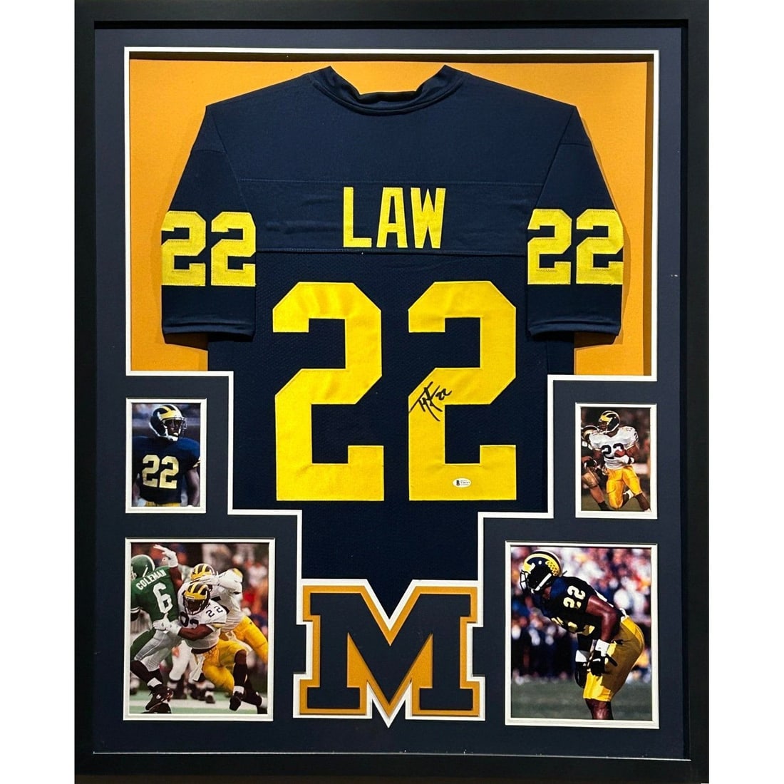 Framed Michigan Jersey Signed by Ty Law Beckett Authenticated: Framed Michigan Jersey Signed by Ty Law Beckett Authenticated This is a framed Michigan jersey autographed by Ty Law, authenticated by Beckett. The display features a UV-protected acrylic front and hi