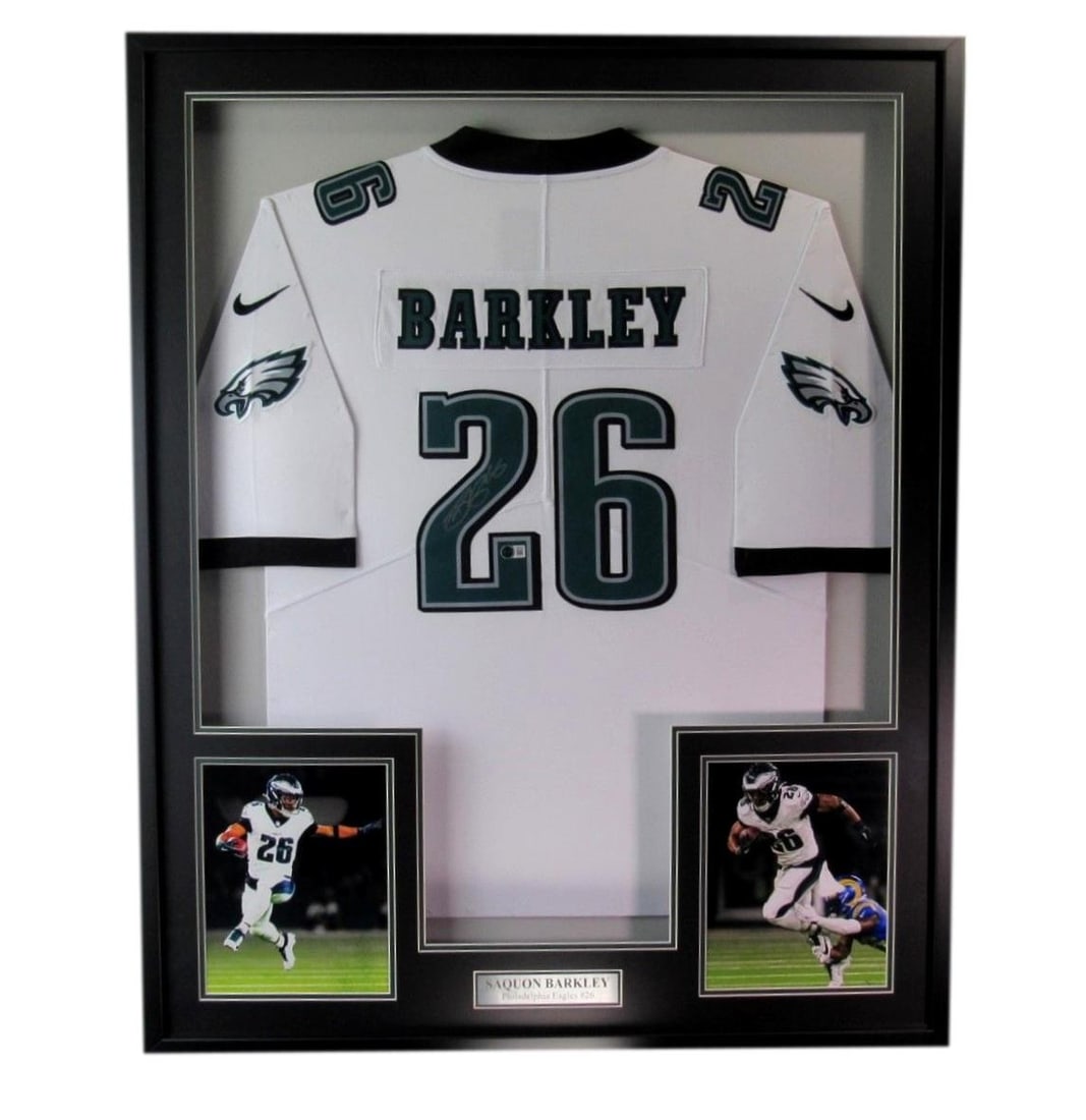 Framed Philadelphia Eagles White Jersey Signed by Saquon Barkley Beckett Authenticated: Framed Philadelphia Eagles White Jersey Signed by Saquon Barkley Beckett Authenticated This offering features a signed Saquon Barkley White Philadelphia Eagles Football Jersey, beautifully framed for 