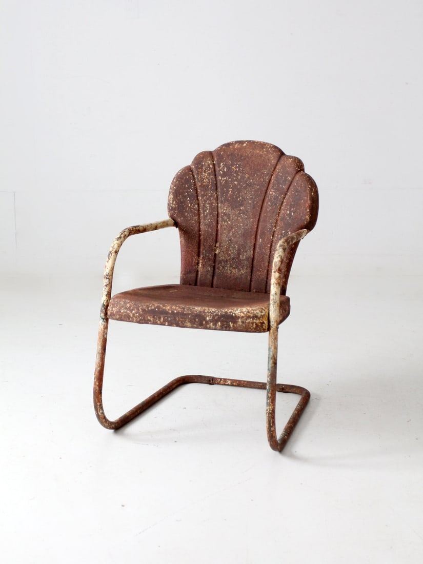 Vintage Mid Century Art Deco Patio Chair Cantilever Design: Vintage Mid Century Art Deco Patio Chair Cantilever Design This mid-century patio chair features a unique art deco design with a cantilever bouncer frame and a seashell-shaped back. The chair exhibits