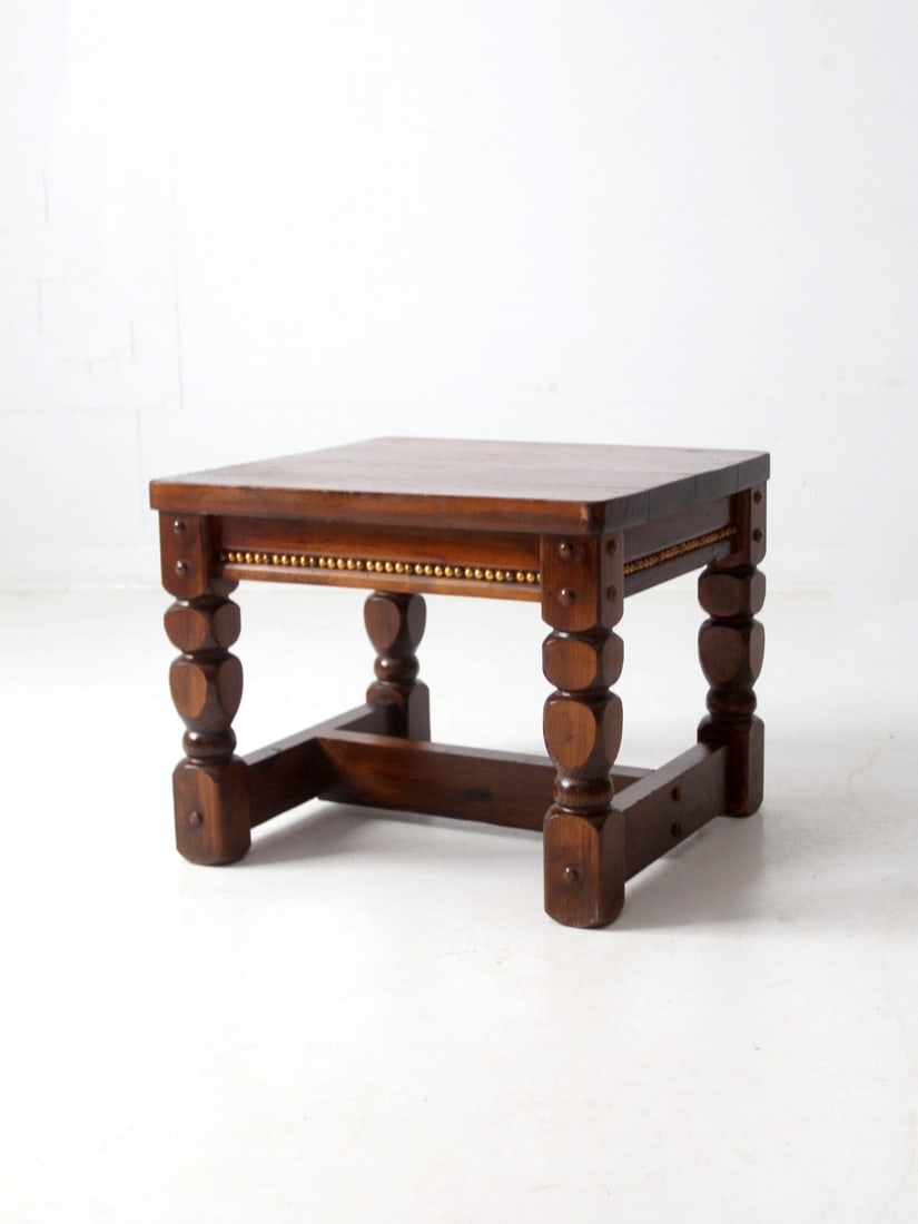 Vintage Lodge Style End Table with Walnut Finish and Gold Accents: Vintage Lodge Style End Table with Walnut Finish and Gold Accents This vintage lodge-style end table showcases a rich walnut finish complemented by distinctive blocky turned legs and subtle gold stud 