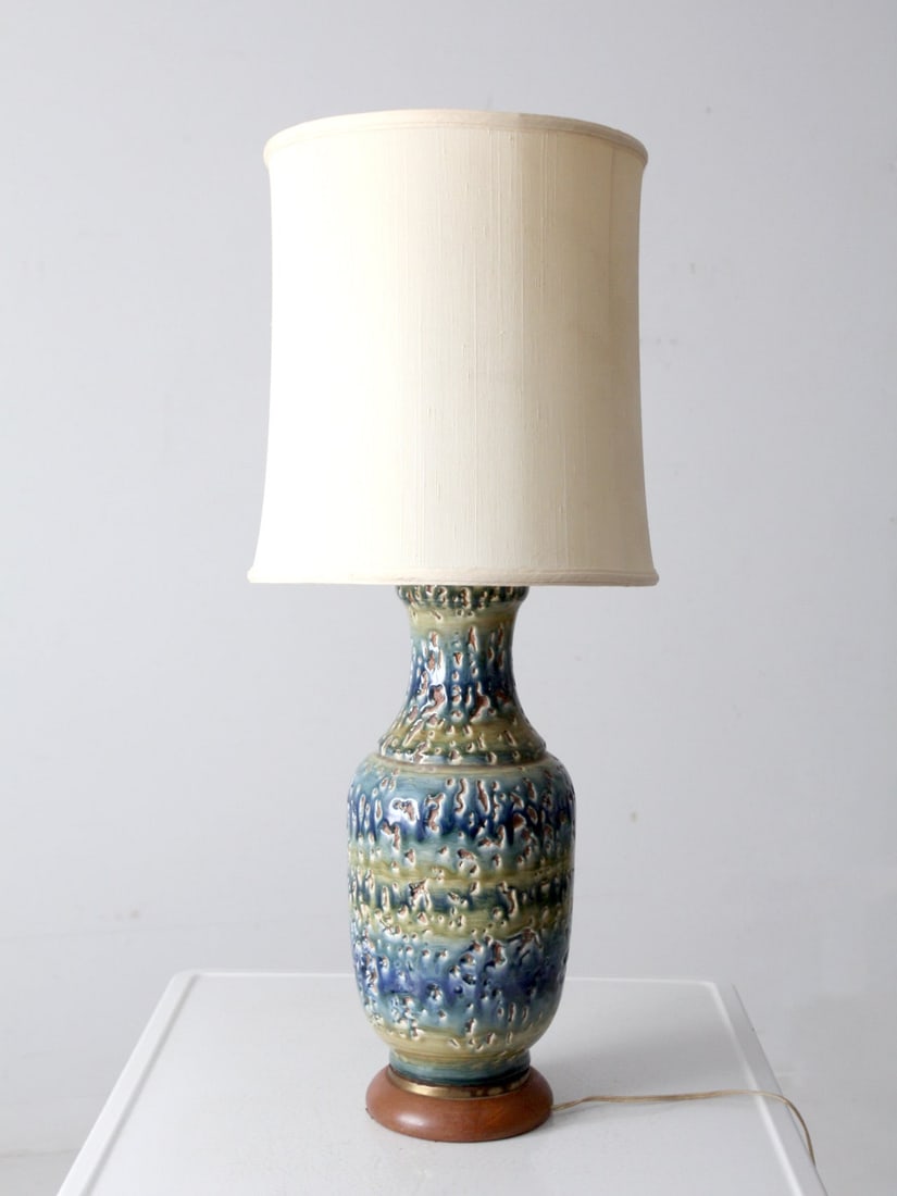 Mid-Century Blue Green Ceramic Table Lamp with Wooden Base: Mid-Century Blue Green Ceramic Table Lamp with Wooden Base This mid-century ceramic table lamp showcases a beautifully textured ceramic base in shades of blue and green, enhanced by a mottled, reactiv