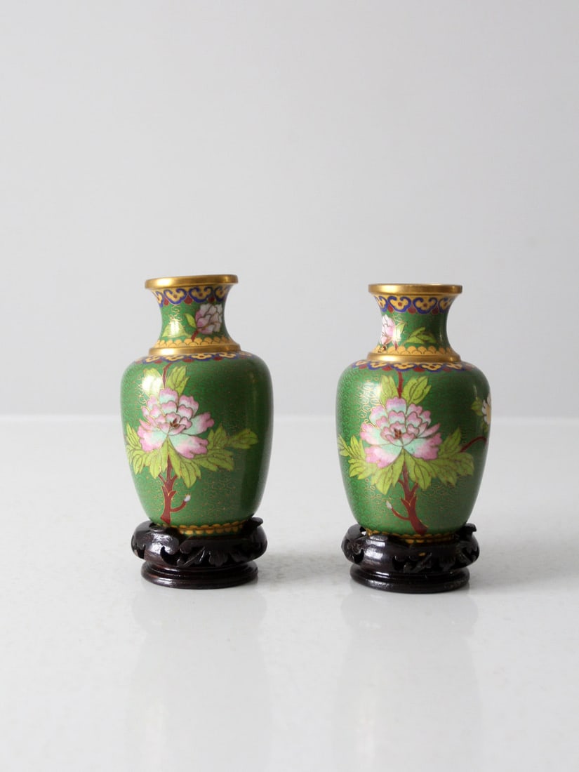 Pair of Vintage Cloisonne Vases with Wood Bases: Pair of Vintage Cloisonne Vases with Wood Bases This exquisite pair of vintage cloisonne vases showcases stunning green enamel and bronze designs, elegantly adorned with delicate pink florals. Each va