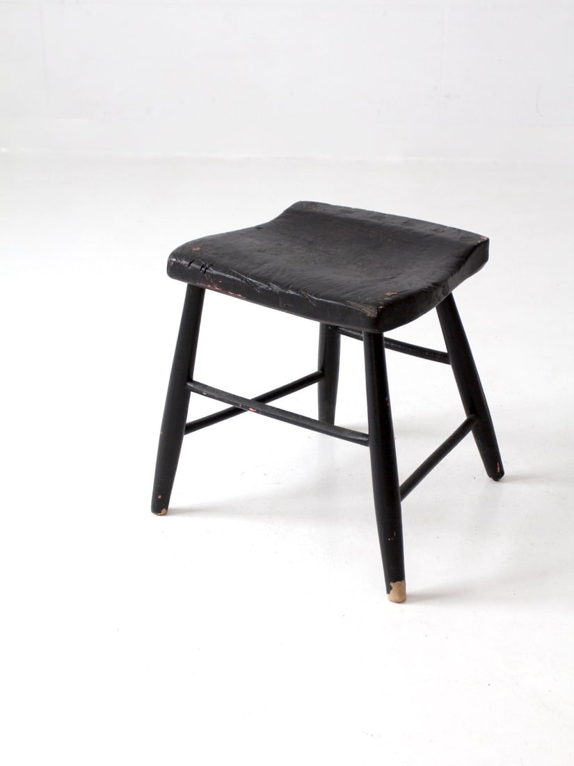 Rustic Antique Black Wooden Stool with Windsor Seat: Rustic Antique Black Wooden Stool with Windsor Seat This antique wooden stool features a charming aged black paint finish, showcasing its rustic character. The seat is shaped like a Windsor chair and 