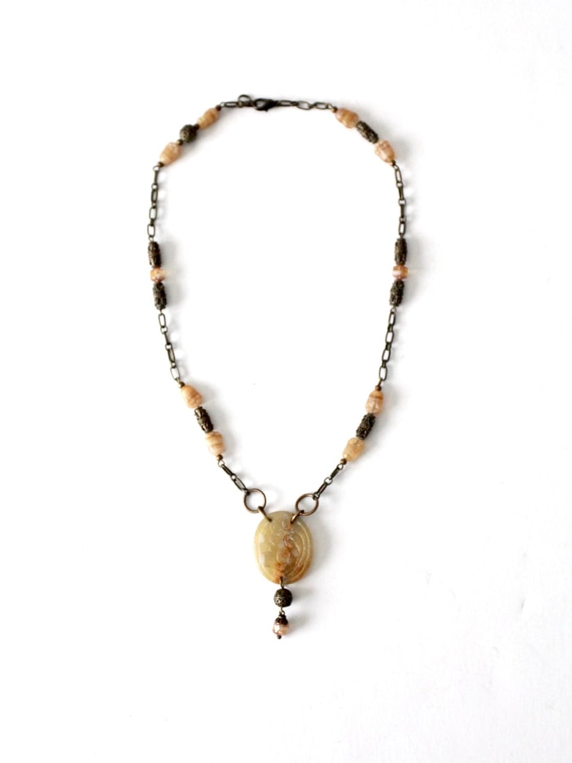 1970s Vintage Boho Beaded Pendant Necklace with Carved Stone: 1970s Vintage Boho Beaded Pendant Necklace with Carved Stone This vintage 1970s pendant necklace showcases a beautifully carved stone pendant complemented by a brassy link chain adorned with beads, em