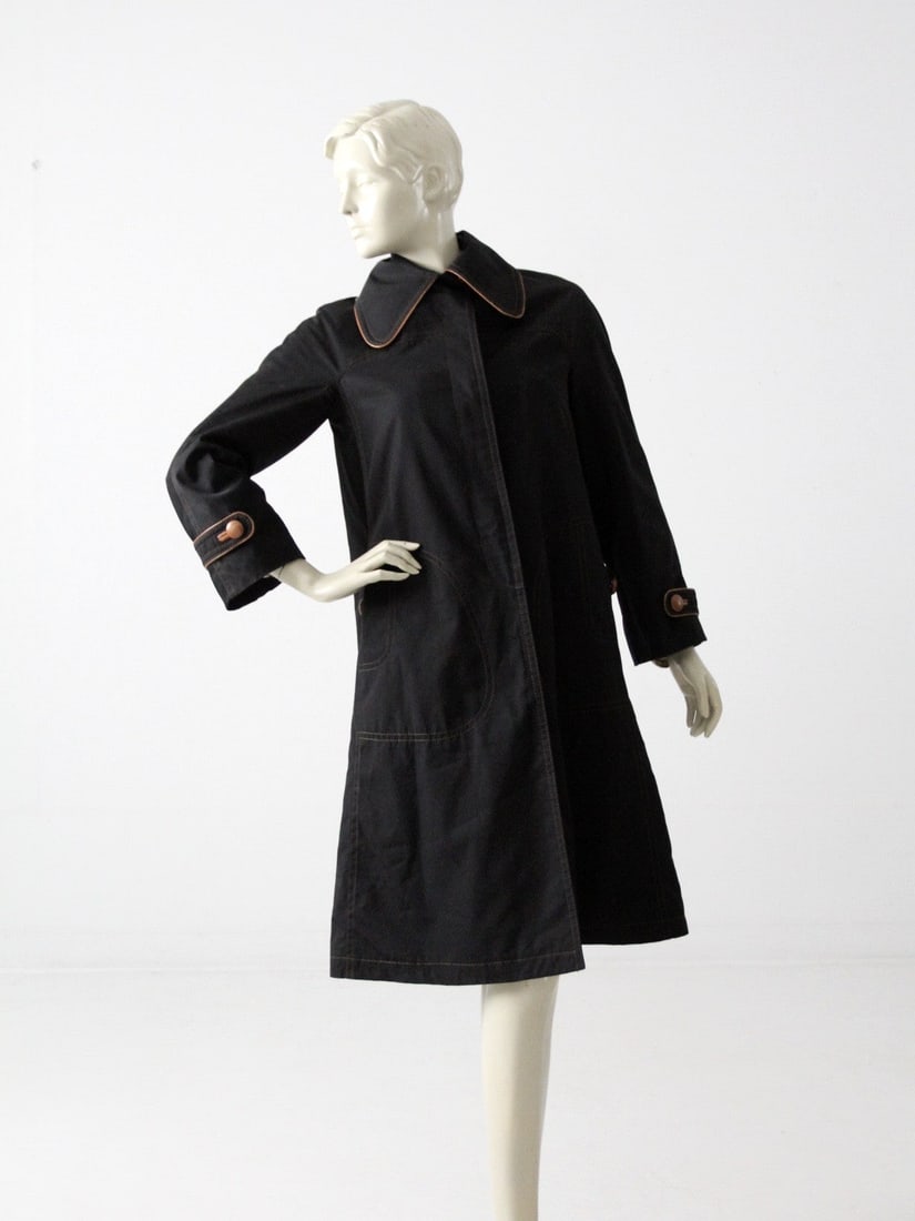 Vintage Cortefiel Black Tan Trench Coat with Leather Trim: Vintage Cortefiel Black Tan Trench Coat with Leather Trim This vintage Cortefiel trench coat is a stylish addition to any wardrobe. The mid-length design features a sophisticated black fabric compleme