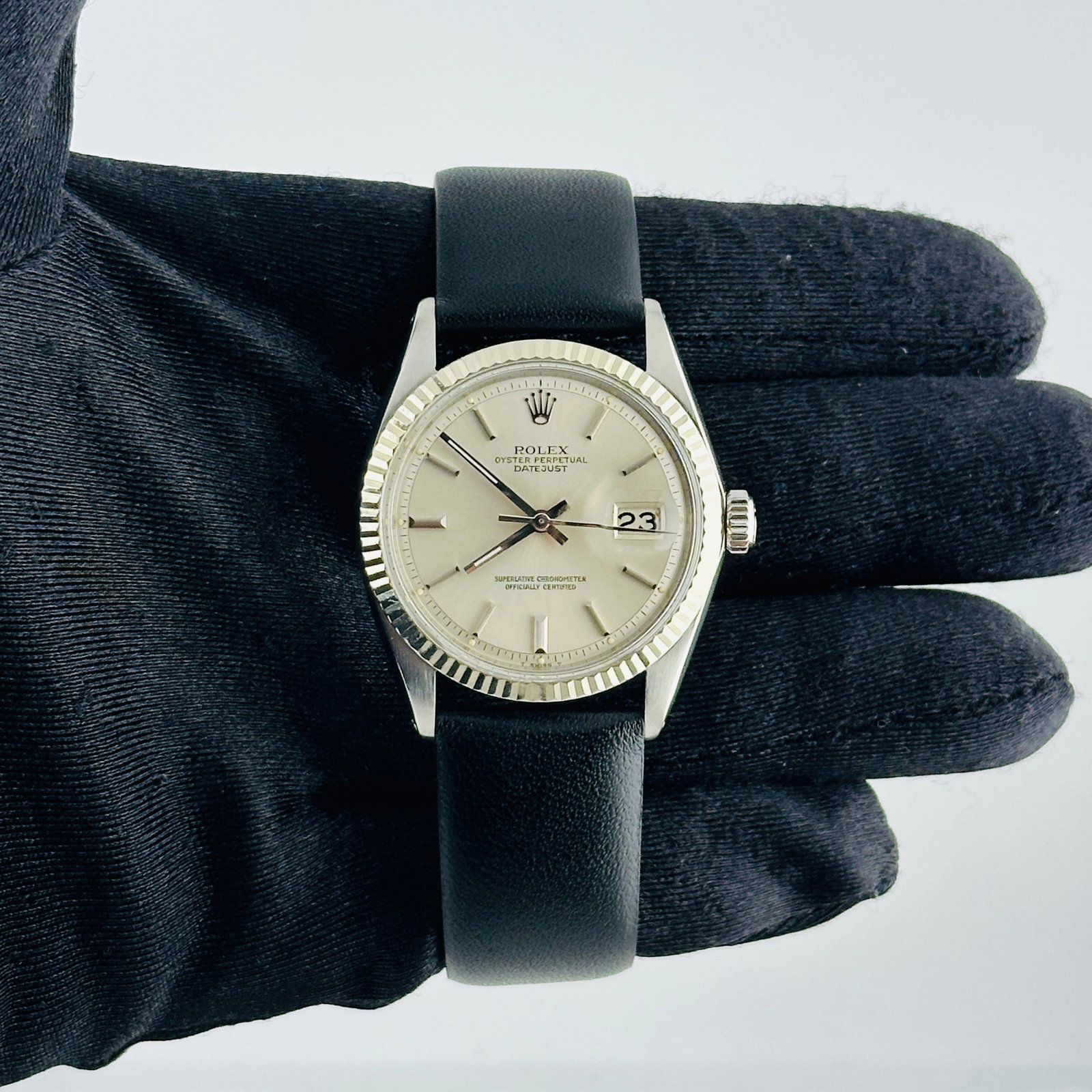 Datejust Reference 1601-3 Silver Stick Dial Mens Watch With Aftermarket Leather Strap: Datejust Reference 1601-3 Silver Stick Dial Mens Watch With Aftermarket Leather Strap This Rolex Datejust watch features a silver stick dial and a fluted bezel, paired with an aftermarket leather brac